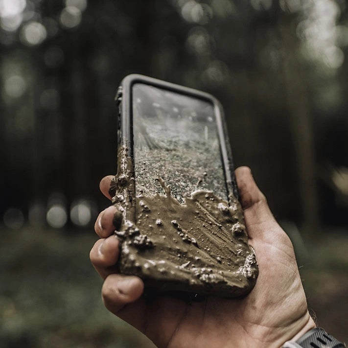 Catalyst iPhone waterproof case black covered in mud while hiking drop proof collection